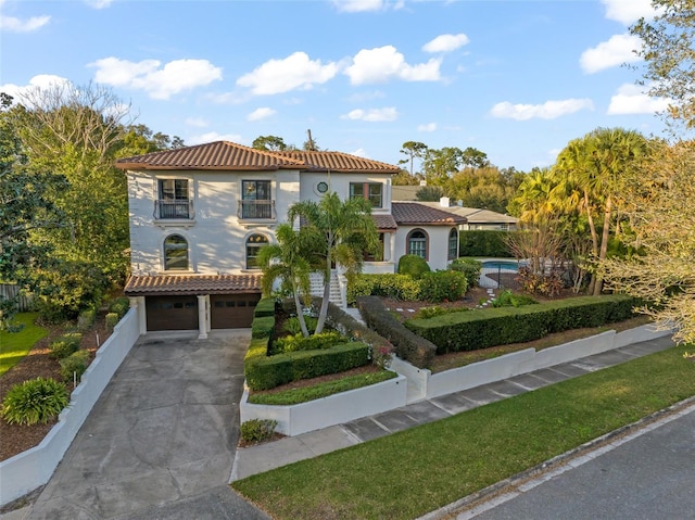 mediterranean / spanish home featuring stucco siding, concrete driveway, an attached garage, and fence