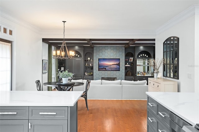 kitchen featuring light countertops, ornamental molding, gray cabinets, an inviting chandelier, and wood finished floors