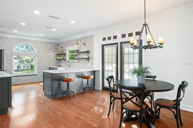 dining room featuring wallpapered walls, crown molding, wood finished floors, and baseboards