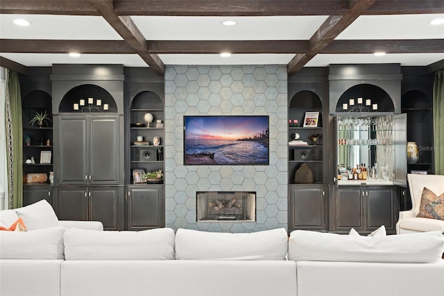 living area featuring a stone fireplace, beamed ceiling, coffered ceiling, and a dry bar