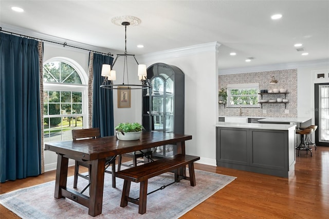 dining space with a notable chandelier, ornamental molding, baseboards, and wood finished floors