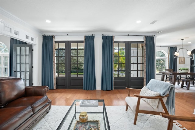 living area with recessed lighting, french doors, a notable chandelier, and wood finished floors