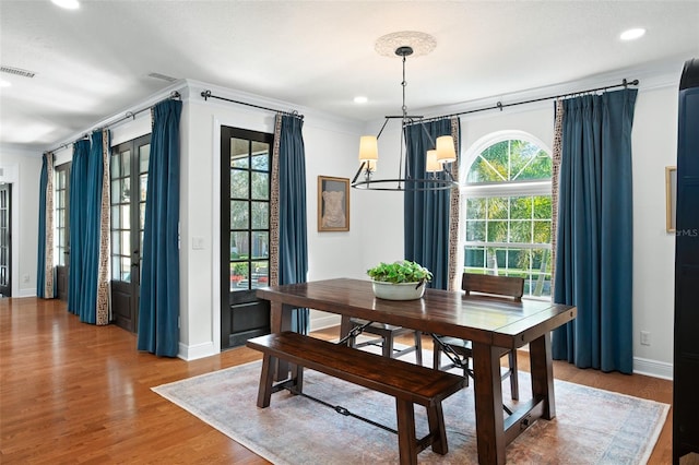 dining room with ornamental molding, wood finished floors, visible vents, and baseboards