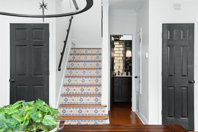 stairway with wood finished floors, baseboards, and ornamental molding