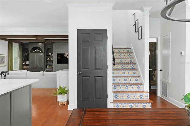 stairs featuring baseboards, wood finished floors, visible vents, and ornamental molding