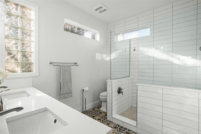 full bath featuring visible vents, toilet, a walk in shower, a sink, and baseboards