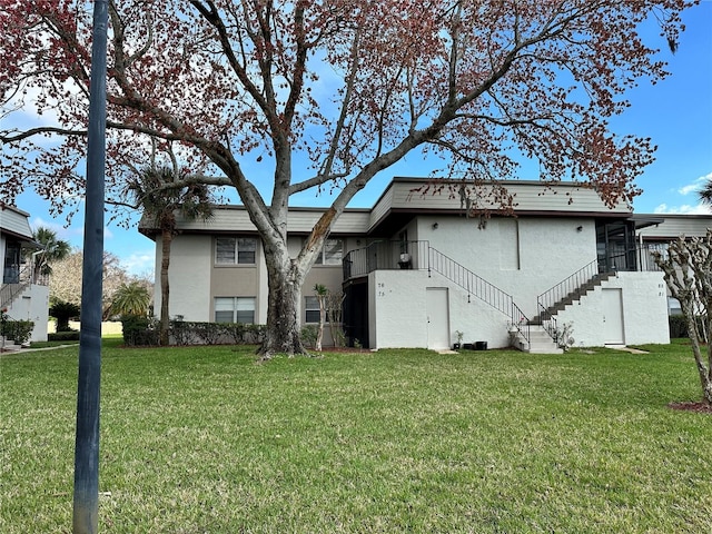 back of property with a yard, stairway, and stucco siding