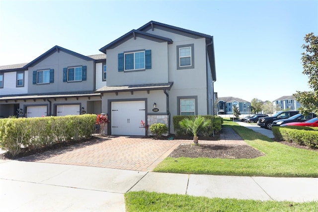 view of front of home featuring decorative driveway, an attached garage, a residential view, and stucco siding