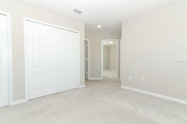 unfurnished bedroom with baseboards, visible vents, a closet, and light colored carpet