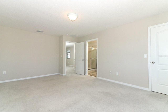 spare room featuring light carpet, visible vents, and baseboards