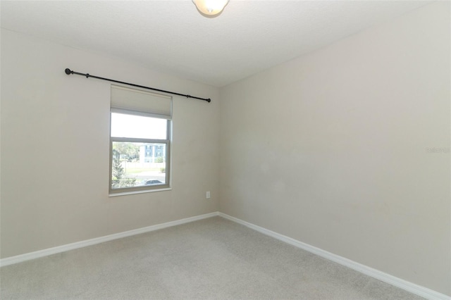 carpeted empty room featuring baseboards