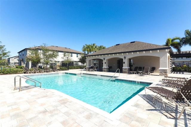 community pool with a patio area and fence