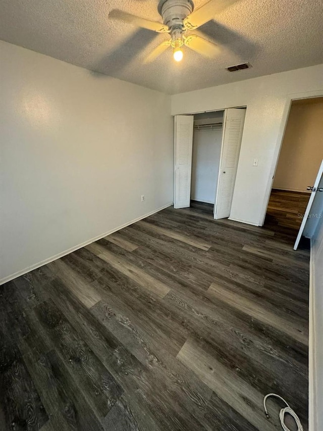 5951 Village Cir Unit Ge, Orlando, FL 32822 - unfurnished bedroom featuring a textured ceiling, a closet, dark wood finished floors, and visible vents