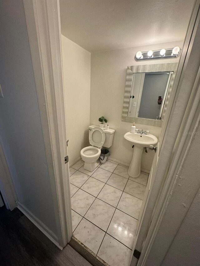 5951 Village Cir Unit Ge, Orlando, FL 32822 - half bathroom featuring toilet, baseboards, a sink, and tile patterned floors