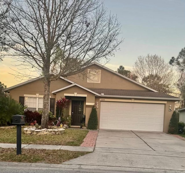 ranch-style home with concrete driveway, an attached garage, and stucco siding