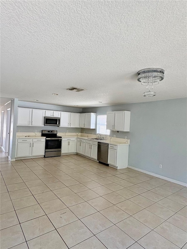 kitchen with light countertops, appliances with stainless steel finishes, visible vents, and white cabinetry