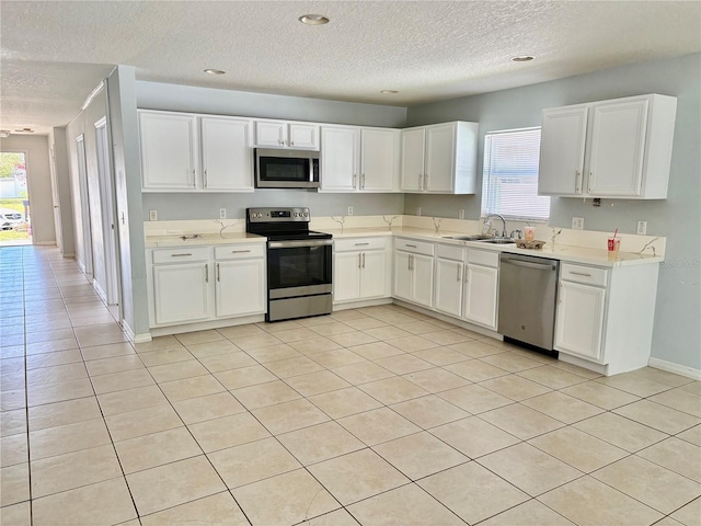 kitchen featuring stainless steel appliances, a sink, light countertops, and white cabinetry