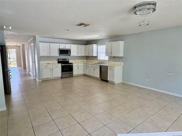 kitchen featuring stainless steel appliances, light countertops, visible vents, white cabinets, and a sink