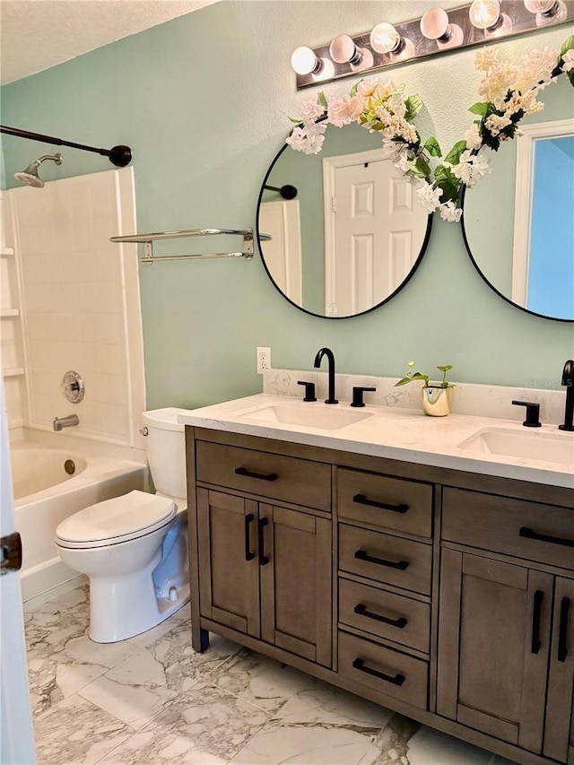 full bath with toilet, marble finish floor, double vanity, and a sink