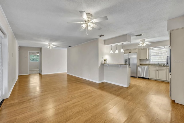 unfurnished living room featuring light wood-type flooring, visible vents, ceiling fan, and a sink