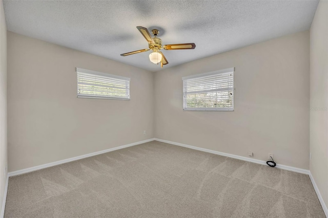 empty room with light carpet, a textured ceiling, a ceiling fan, and baseboards