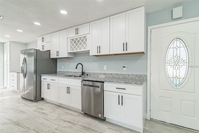 kitchen with sink, white cabinetry, a textured ceiling, stainless steel appliances, and light stone countertops