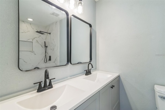 bathroom featuring toilet, vanity, and tiled shower