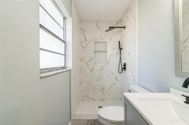 bathroom featuring toilet, vanity, plenty of natural light, and tiled shower