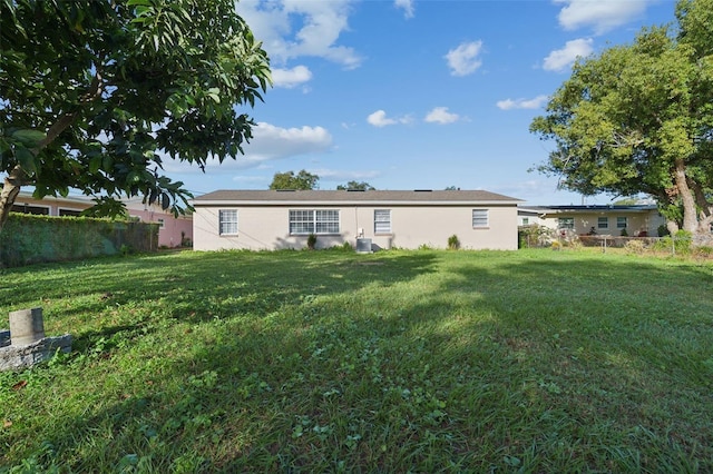 rear view of property with a lawn and cooling unit