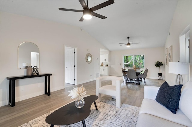 living room with ceiling fan, light hardwood / wood-style flooring, and vaulted ceiling