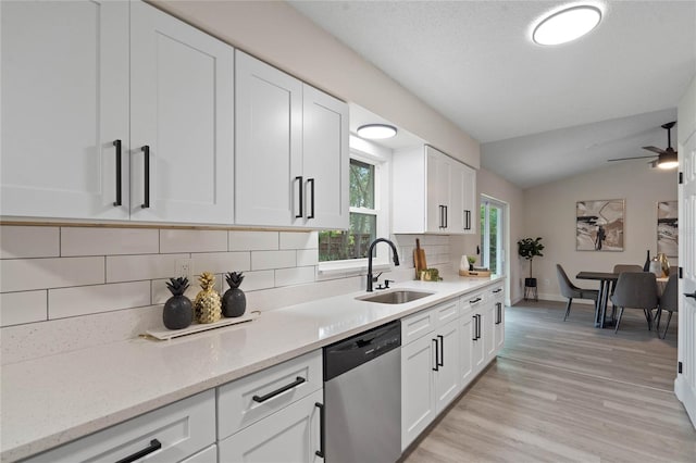 kitchen with sink, stainless steel dishwasher, white cabinetry, and light stone countertops