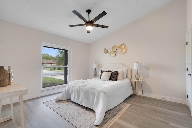 bedroom featuring light hardwood / wood-style floors, vaulted ceiling, and ceiling fan