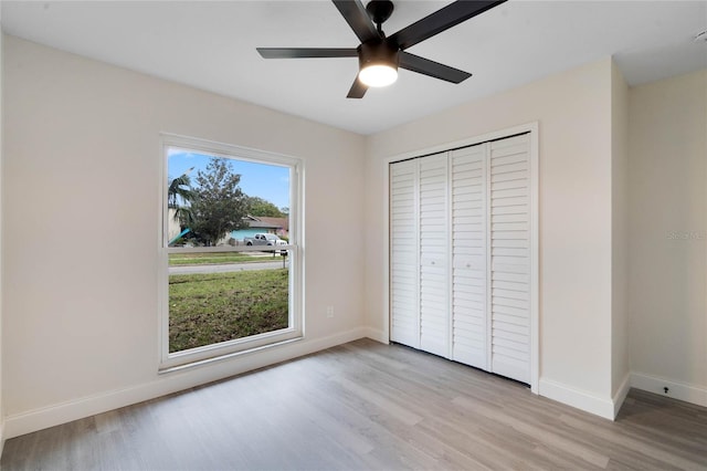 unfurnished bedroom with ceiling fan, light wood-type flooring, and a closet