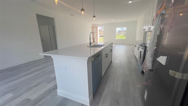 kitchen featuring hardwood / wood-style flooring, an island with sink, stainless steel appliances, sink, and white cabinetry