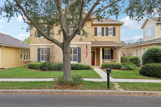 view of front of property with a porch, a front yard, a shingled roof, and stucco siding