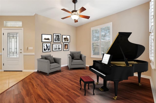 living area featuring wood finished floors, a ceiling fan, and baseboards