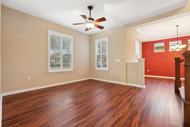 spare room with dark wood-type flooring, plenty of natural light, baseboards, and ceiling fan with notable chandelier