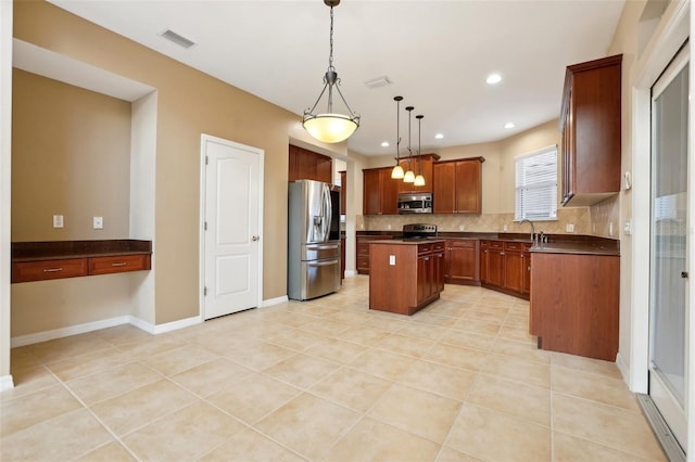 kitchen with a center island, stainless steel appliances, dark countertops, visible vents, and hanging light fixtures