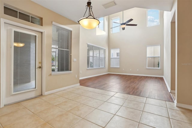 unfurnished room with light tile patterned floors, a high ceiling, visible vents, a ceiling fan, and baseboards