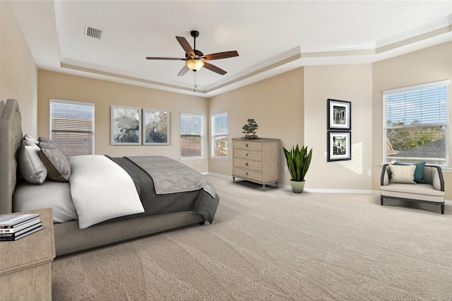 bedroom with a raised ceiling, light colored carpet, visible vents, and baseboards