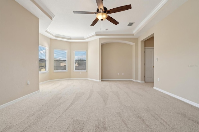 spare room with a raised ceiling, ornamental molding, a ceiling fan, light carpet, and baseboards