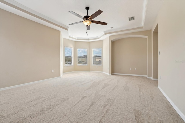 unfurnished room featuring light carpet, visible vents, a ceiling fan, baseboards, and a tray ceiling