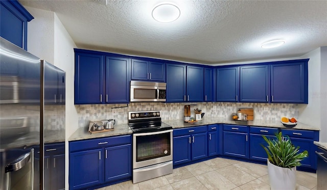 kitchen with appliances with stainless steel finishes, blue cabinets, backsplash, and light stone countertops