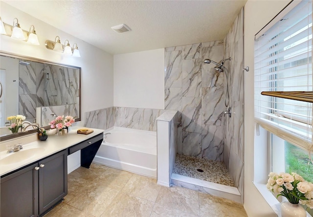 full bath with a textured ceiling, a garden tub, a marble finish shower, and vanity