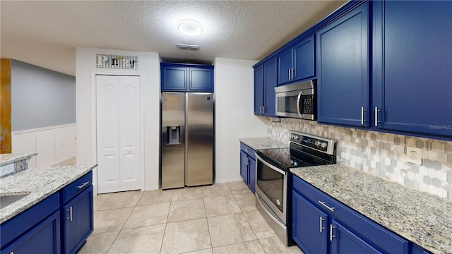 kitchen with light stone counters, light tile patterned floors, stainless steel appliances, visible vents, and blue cabinets