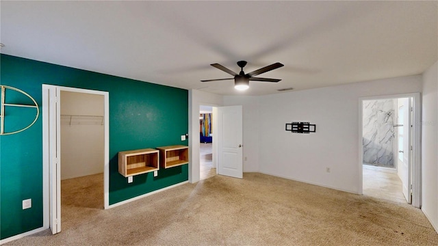 unfurnished bedroom featuring light carpet, visible vents, a ceiling fan, a walk in closet, and a closet