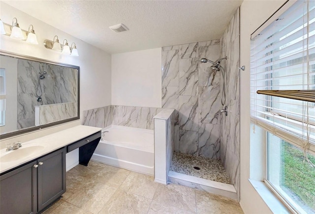 bathroom featuring a garden tub, a marble finish shower, a textured ceiling, and vanity