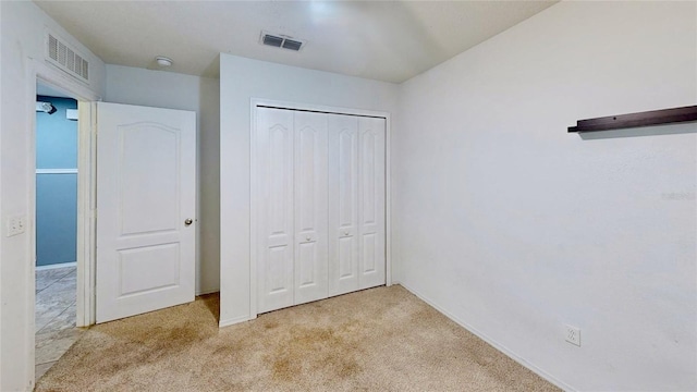 unfurnished bedroom with a closet, visible vents, and light colored carpet