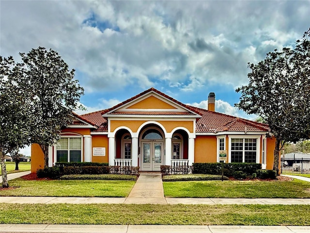 mediterranean / spanish home with a tiled roof, a porch, a chimney, and stucco siding