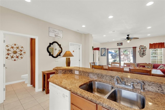 kitchen featuring recessed lighting, a ceiling fan, white dishwasher, a sink, and light stone countertops